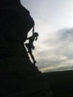Janey silhouetted soloing the route
