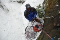 Dave belaying on the ledge of Curving Cracks (VS 4c), Heptonstall, during a snowstorm.