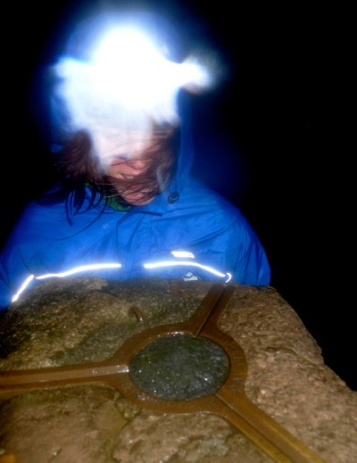 Sally Wheatley, using the TIKKA XP² at the trig point on Helvellyn during a dark and stormy night in December.  © Mick Ryan - UKClimbing.com