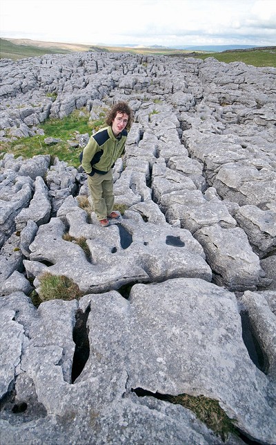 Adam Ondra exploring the deeply eroded limestone pavement atop Malham Cove in Yorkshire  © Vojtech Vrzba