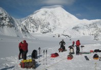 Rigging sleds ready to leave basecamp and start ascent of Denali; Mount Foraker in background