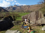 Climber's on The Overhang (V5) with the Langdale Pikes in the distance.