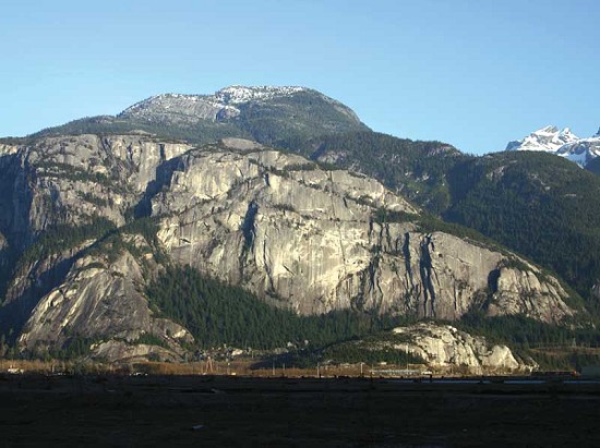 The Chief, as seen from the Squamish estuary. The main bouldering zone is in the forest directly below the whitish wall.  © Marc Bourdon