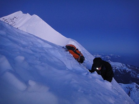 Jack Geldard digging a snow tunnel in the summit ridge of the Eiger. The summit is visible behind and to the left.  © Rob Greenwood