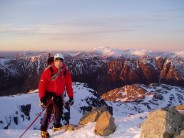 Me at the top of Dorsal Arete, with the Aonach Eagach ridge and Ben Nevis in the background