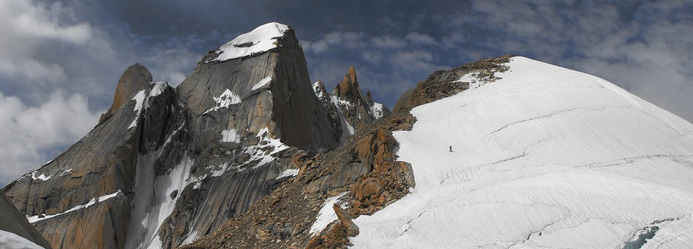 Climber descends from the summit of Samgyal 1 in Ladakh, the (currently) unclimbed spires of Jungdung Kangri in the background.  © Wildcountryconsultants.co.uk