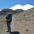 Load carrying to ABC on Mount Elbrus with the twin peaks on the horizon