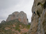 Climber at sector Coll Piqué with Paret del Grau apparent beyond
