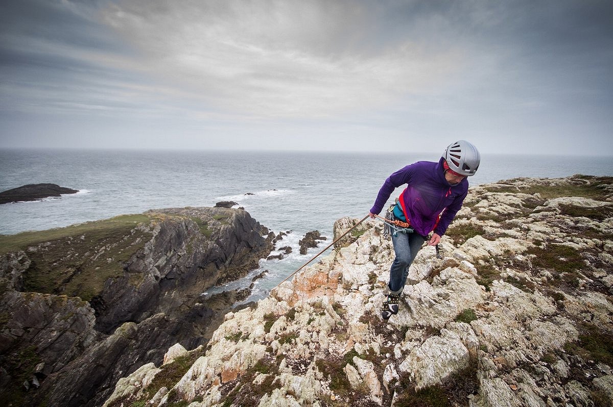 Libby Peters topping out on a windy day at Rhoscolyn  © Rab