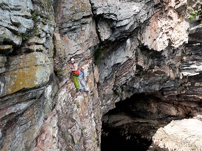 The belay at the end of the 's**t band’ - The Great Cave yawns beneath.  © James Mann