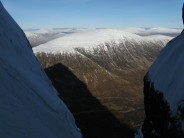 View out of Crowberry Gully as sun begins to set, casting a shadow of Buchaille Etive Mor across the valley.
