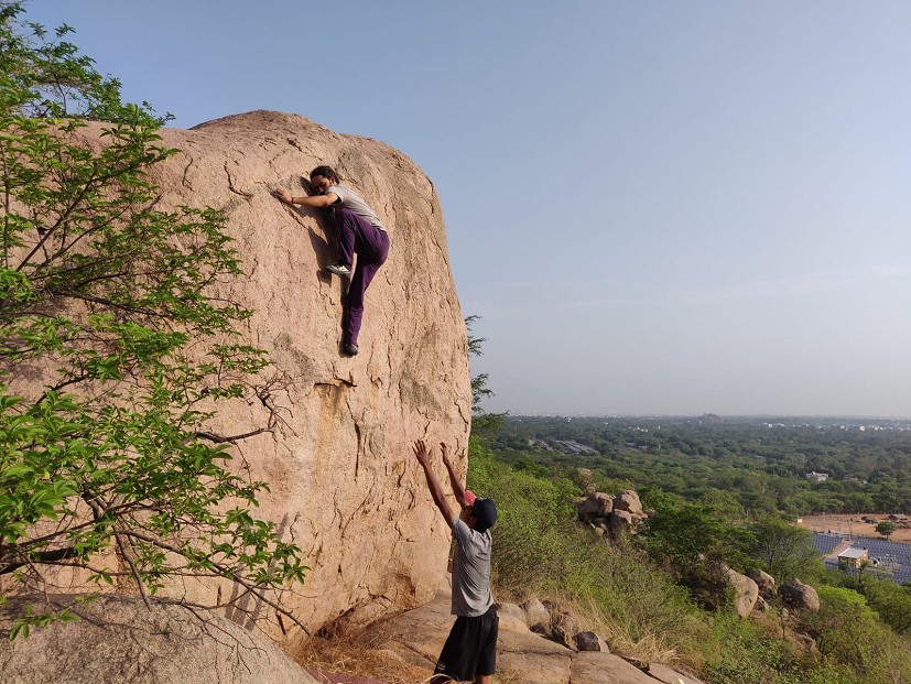 Climbers attempting 6a+ to 6b lines on high boulders. Iconic rock with a quality grade line. East side of the city is visible.  © Raghava Poojari