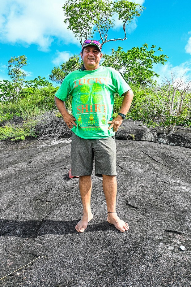Leroy Ignacio stands above some ancient rock carvings.  © Alex Outhwaite
