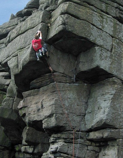 Thea on the crux moves of the imposing Black Hawk Bastion (E2 5c) at Stanage  © Penny Allchin