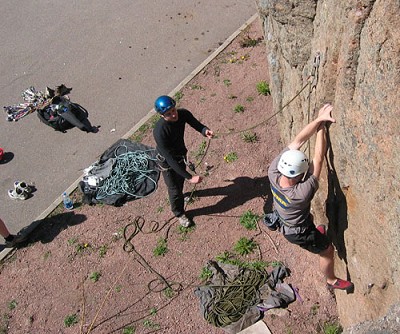 Simon Bell climbing at Langinkoski, Kotka, Finland.  Jody Wren belays and the Snapack lurks behind him.  © TobyA